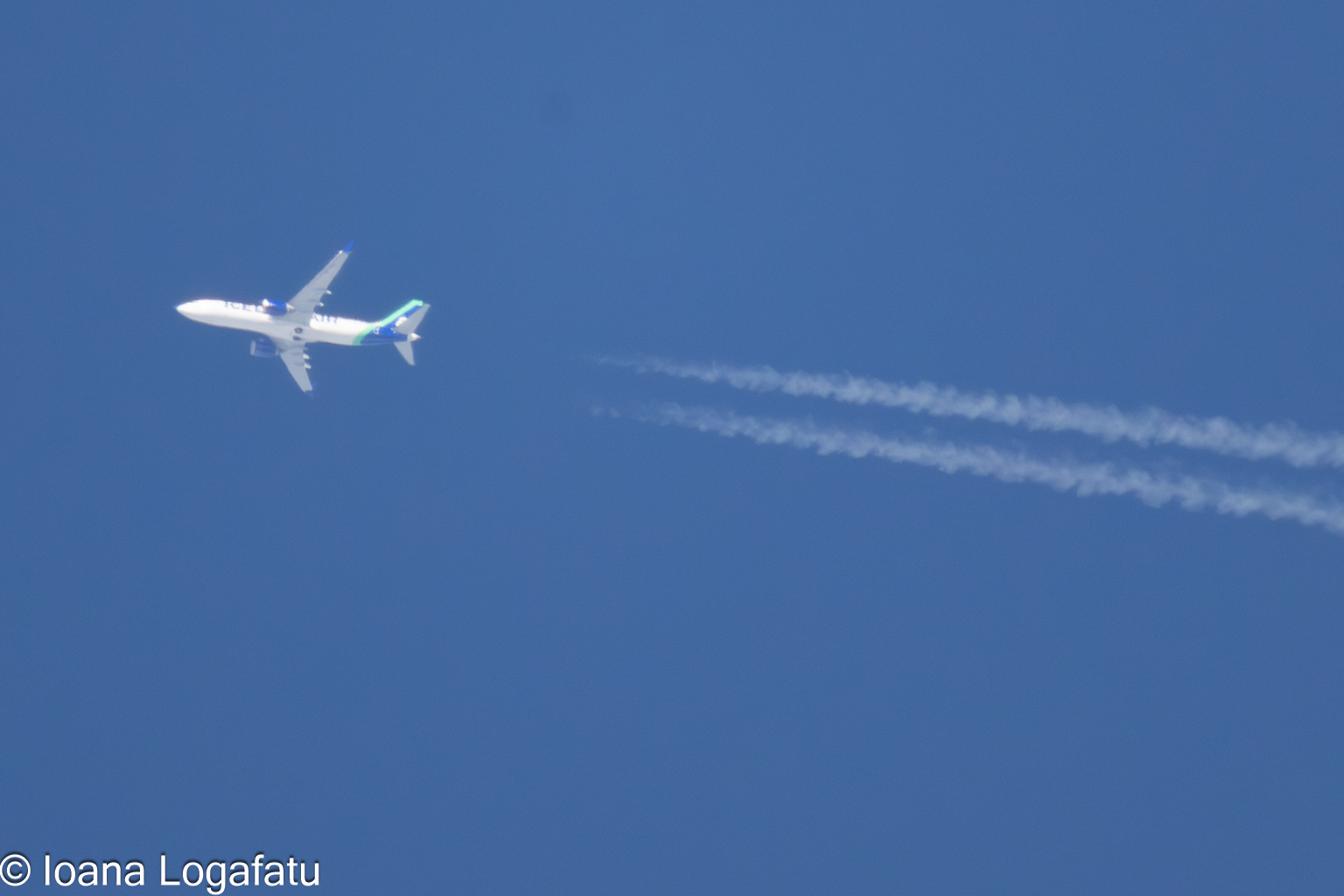 High above, a plane traces clouds in the sky